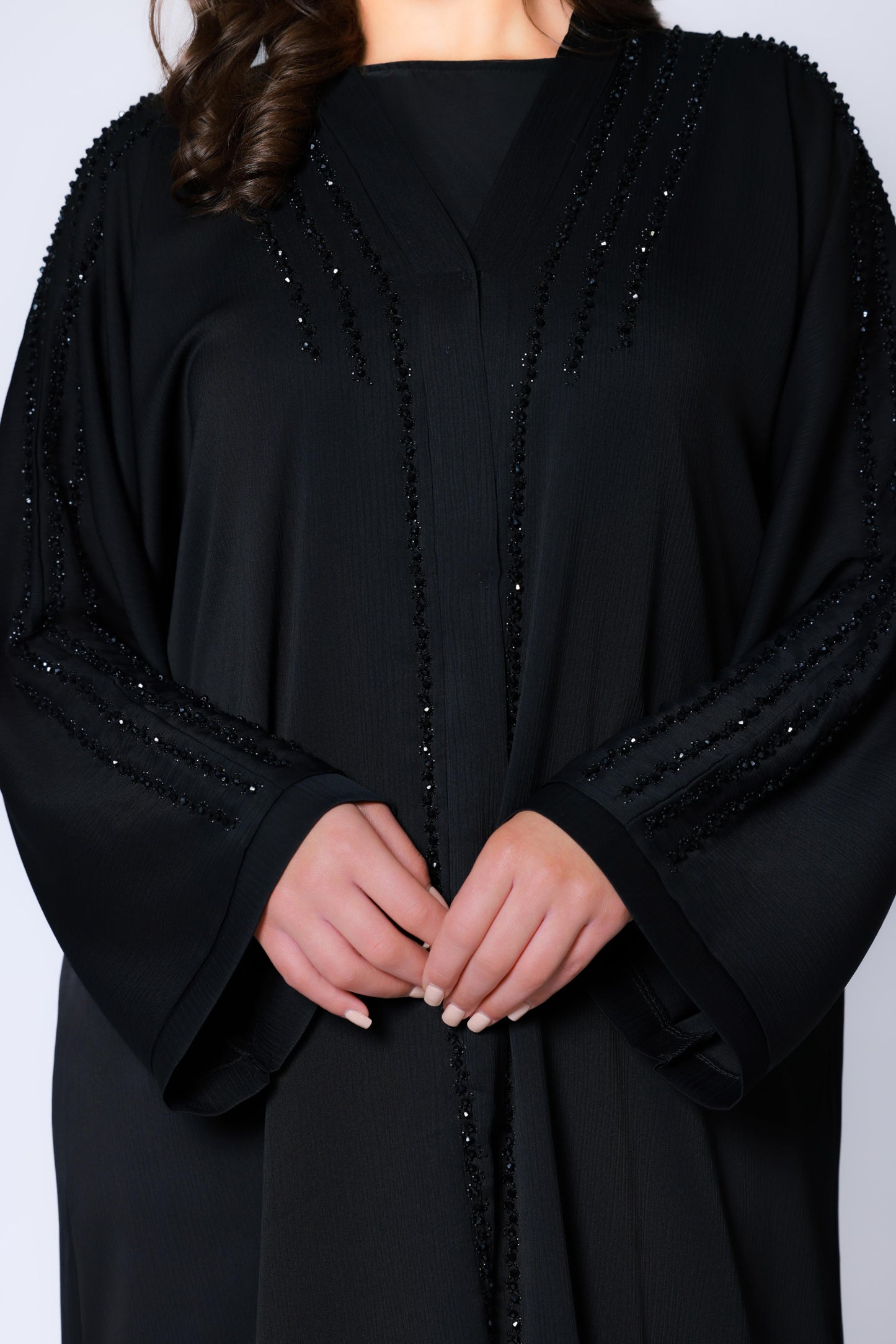 Detailopname van een abaya dames zwart met verfijnd borduurwerk en subtiele glans