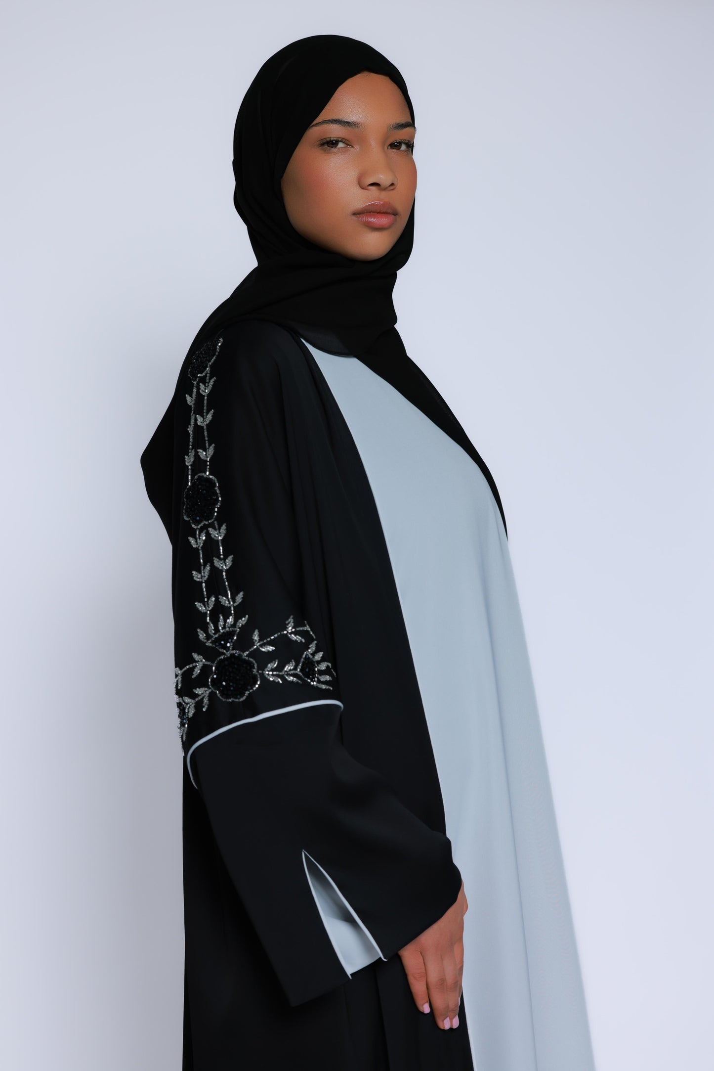 Model met zwarte abaya met contrasterend bloemenborduurwerk en zachte, vloeiende stof