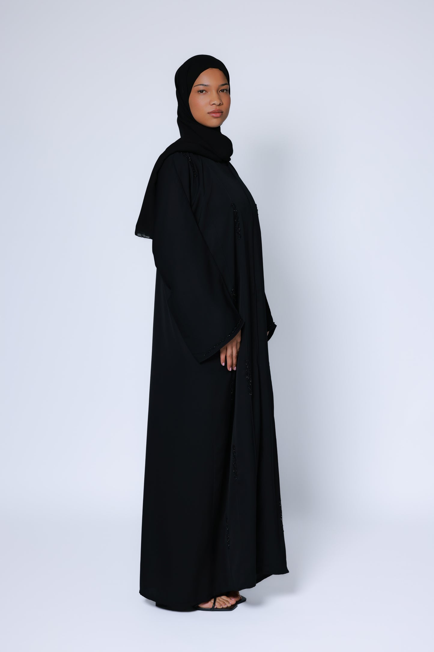 Zwarte abaya met rechte snit en lange mouwen, gedragen met eenvoudige zwarte sandalen