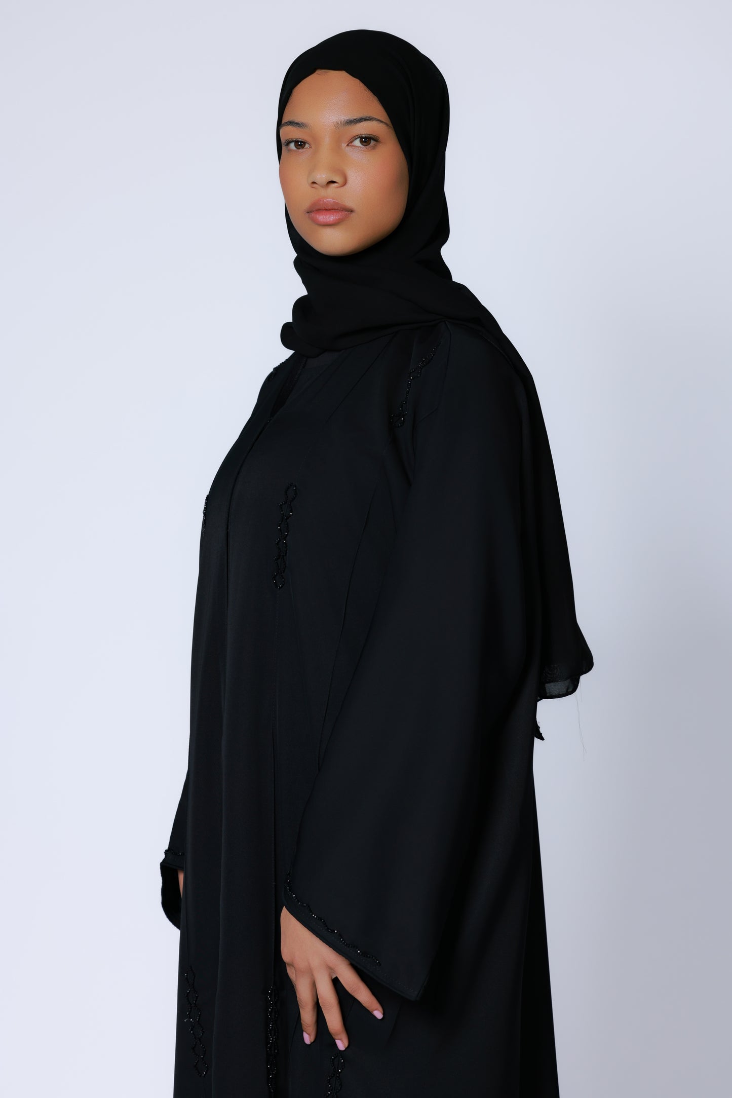 Zijaanzicht van zwarte abaya met decoratieve verticale accenten
