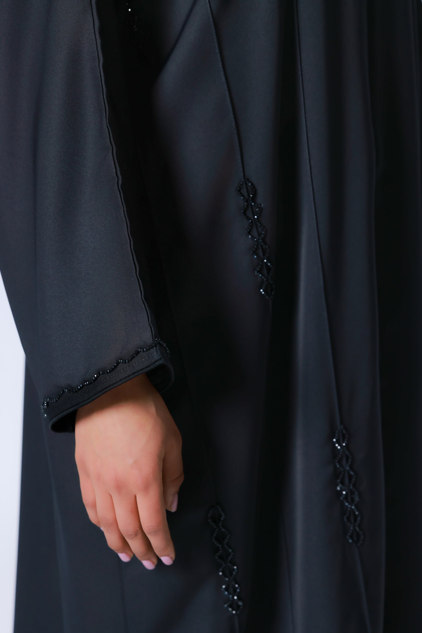 Detailopname van kraaldetails op abaya en mouw van zwarte abaya