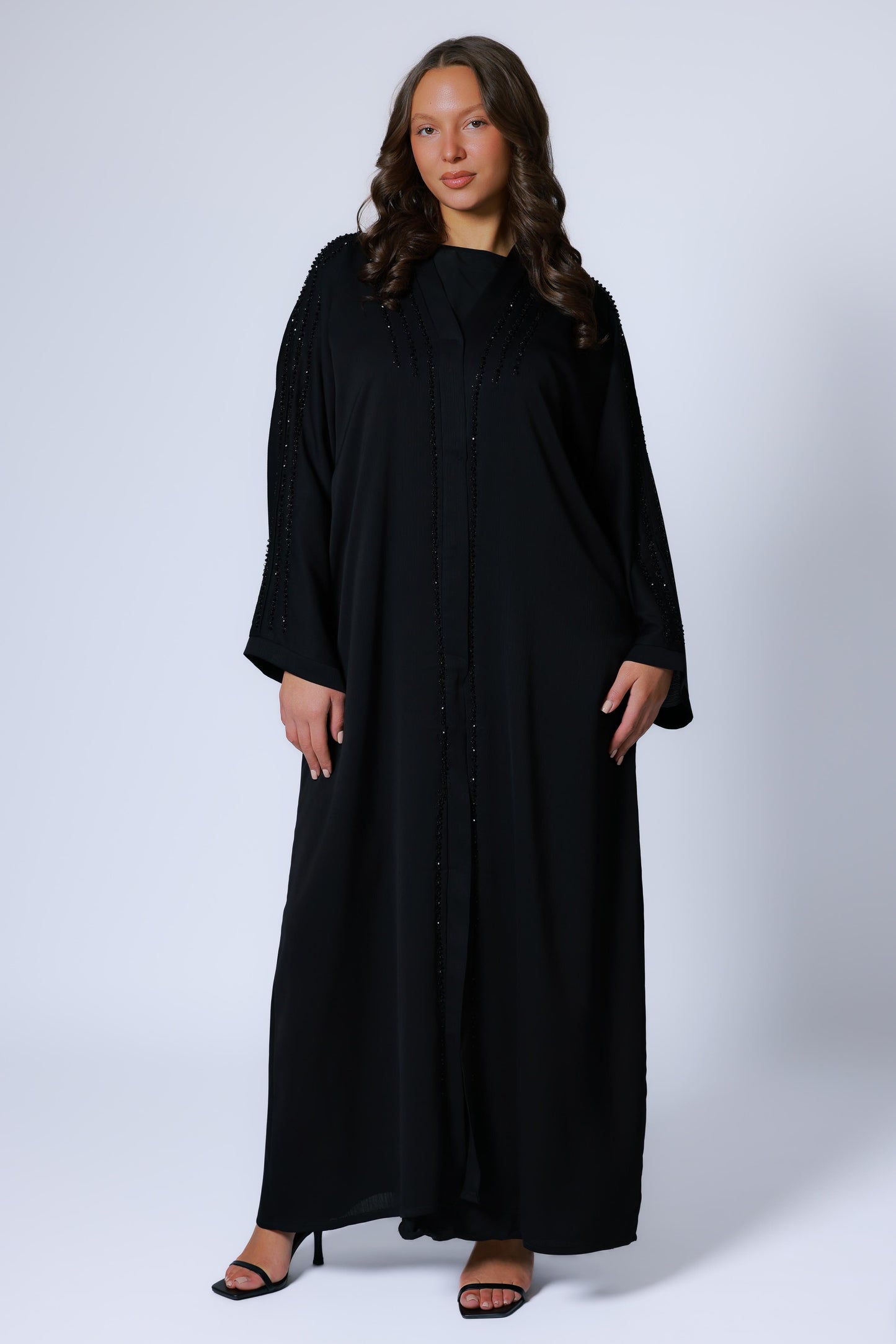 Abaya dames zwart met elegante kimono-snit, gedragen in staande pose met neutrale achtergrond