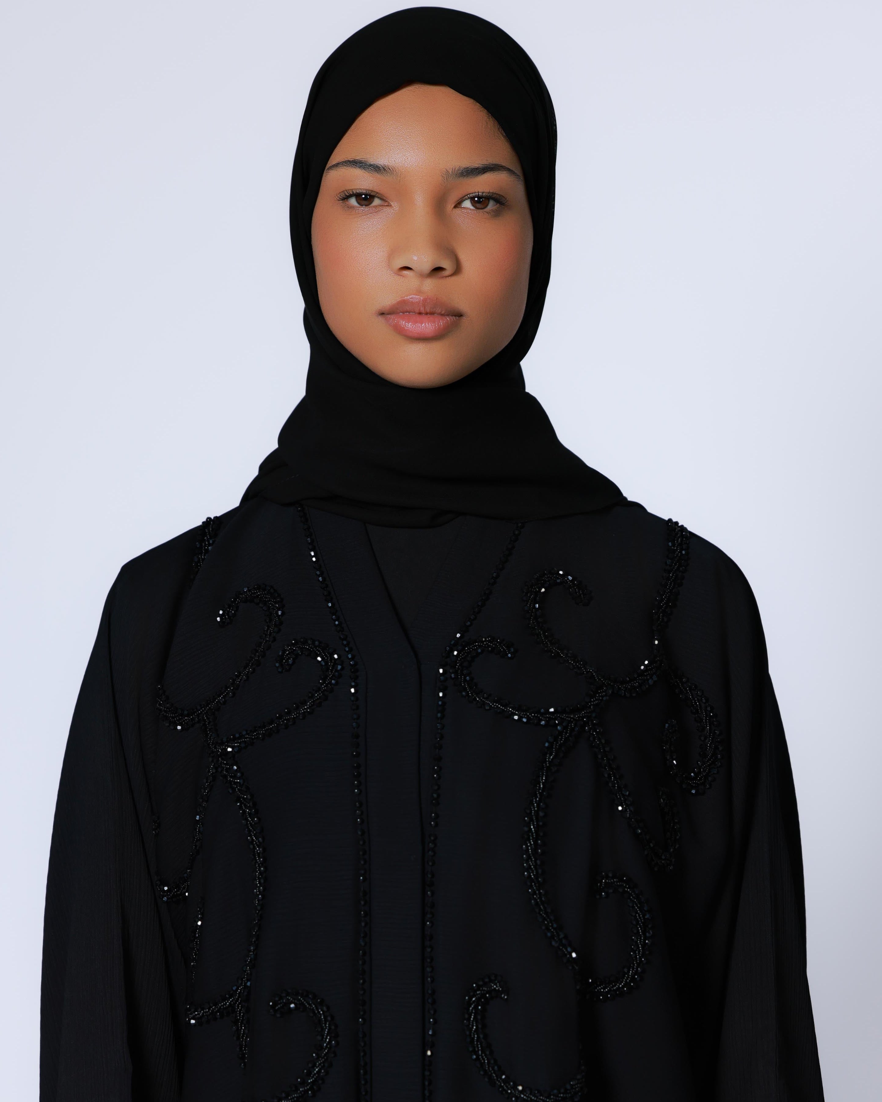 Vrouw in zwarte abaya op neutrale achtergrond