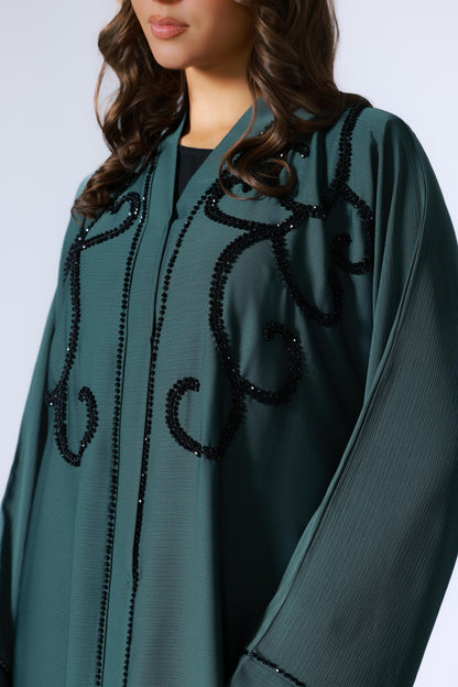 Close-up van steentjes op donkergroene abaya, subtiel fonkelend patroon