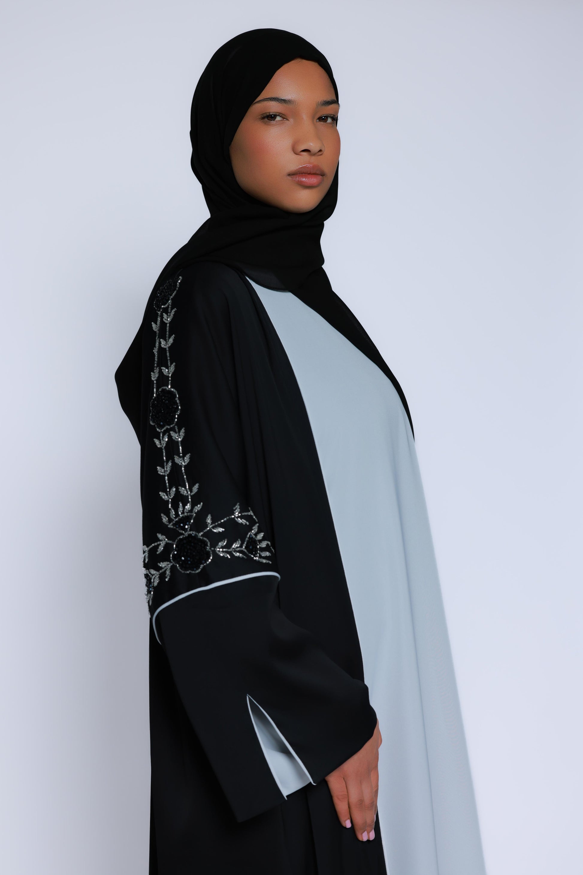 Model met zwarte abaya met contrasterend bloemenborduurwerk en zachte, vloeiende stof
