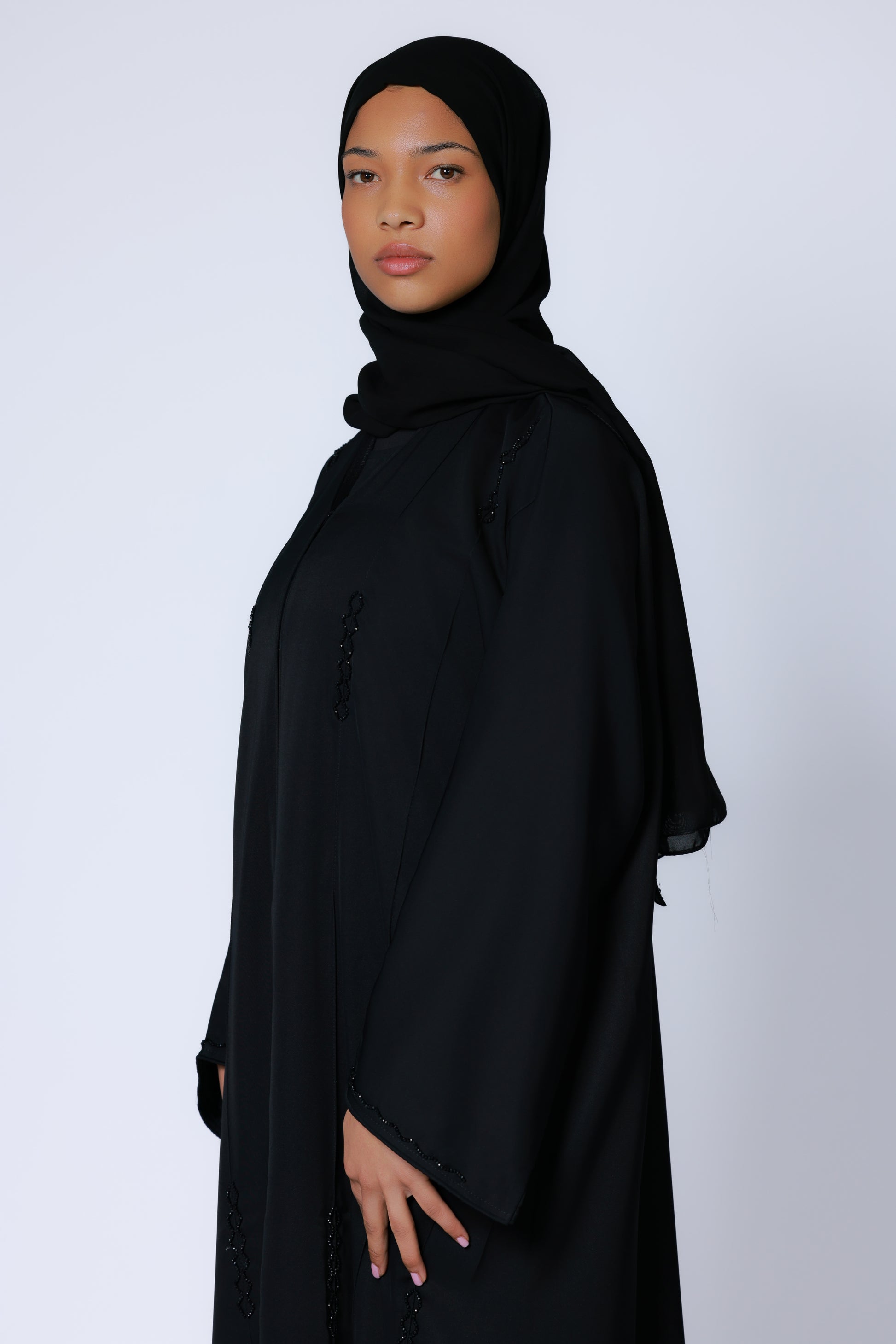 Zijaanzicht van zwarte abaya met decoratieve verticale accenten