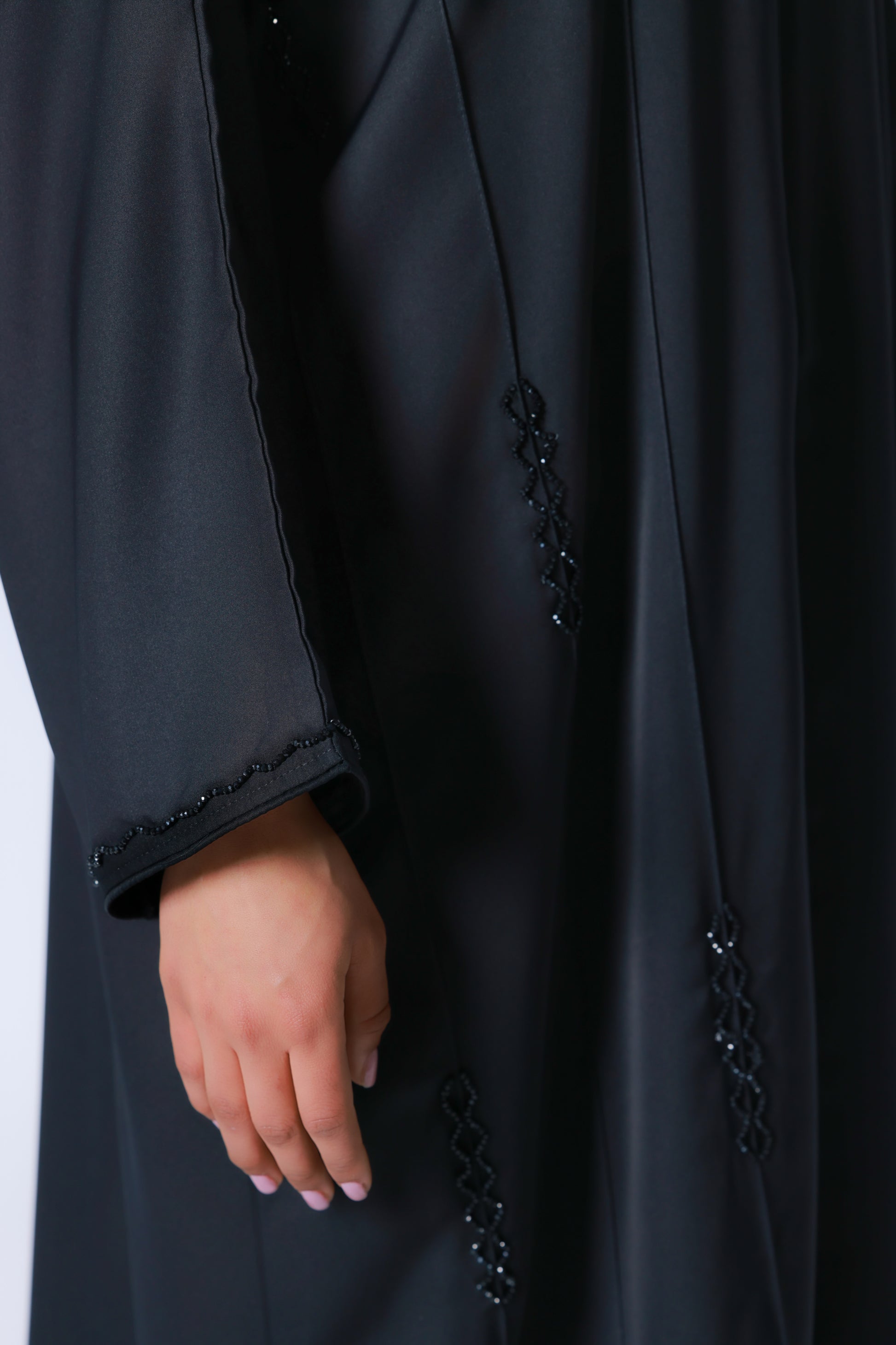 Detailopname van kraaldetails op abaya en mouw van zwarte abaya