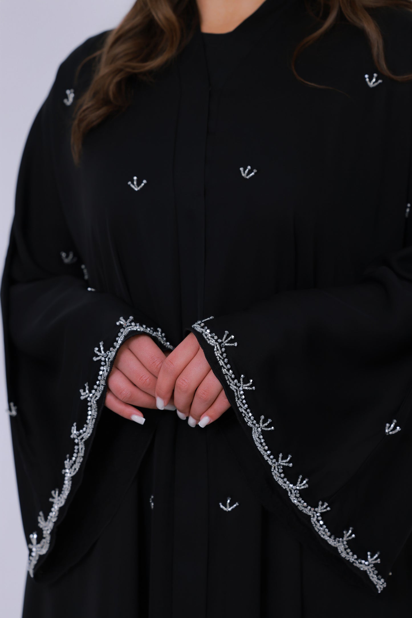 Close-up van zwarte abaya mouwrand met fijn zilverkleurig borduurwerk