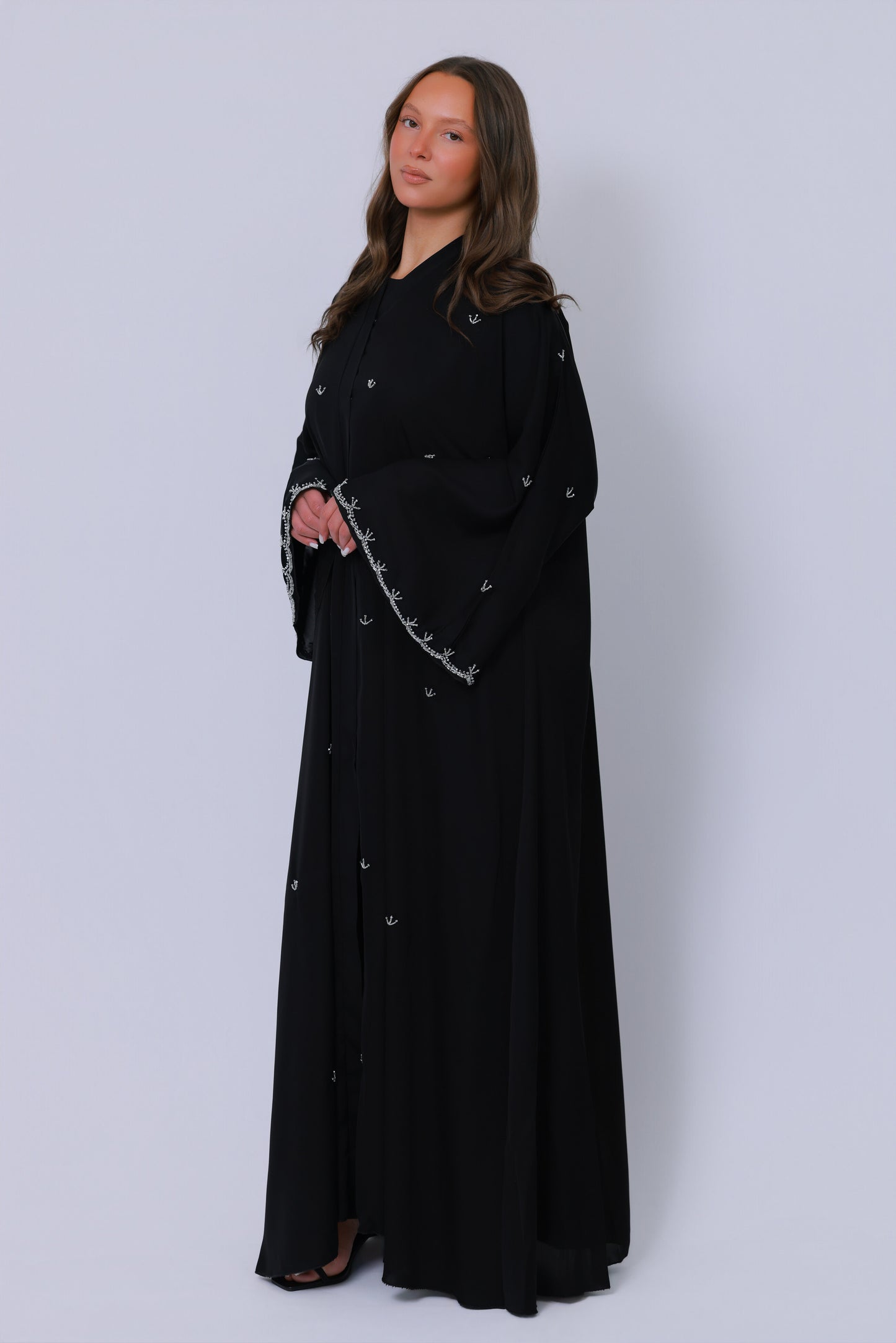 Zwarte open abaya in schuin perspectief met sierlijk borduurwerk langs de mouwen