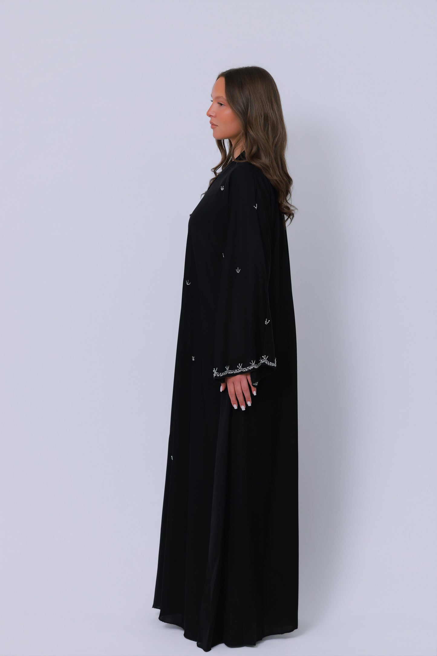 Zwarte abaya zijaanzicht, losvallend silhouet met geborduurde mouwafwerking