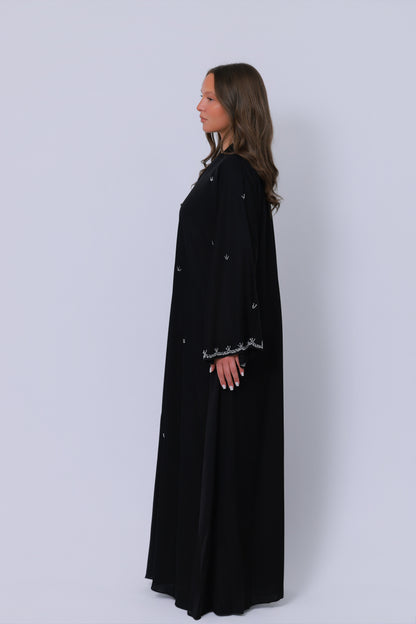 Zwarte abaya zijaanzicht, losvallend silhouet met geborduurde mouwafwerking