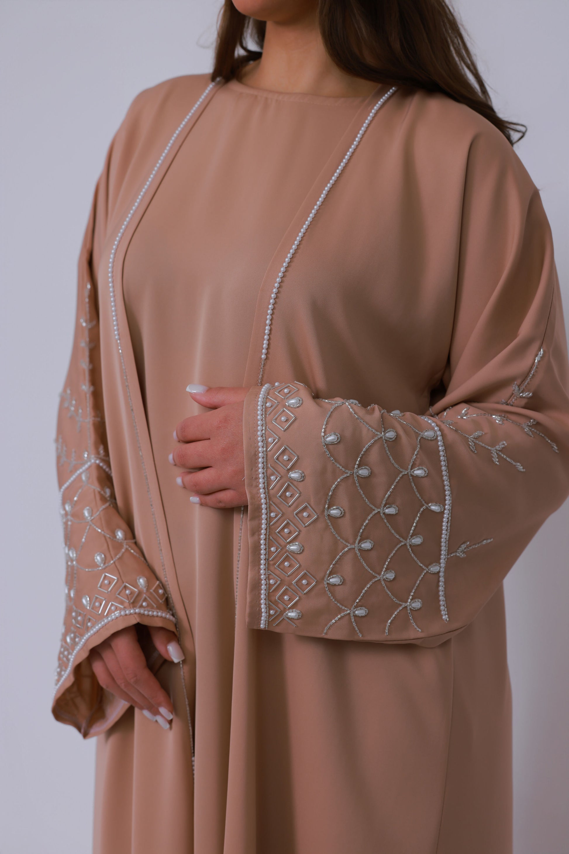 Bovenlichaam van nude beige abaya met parelrand en subtiel geborduurde mouwen
