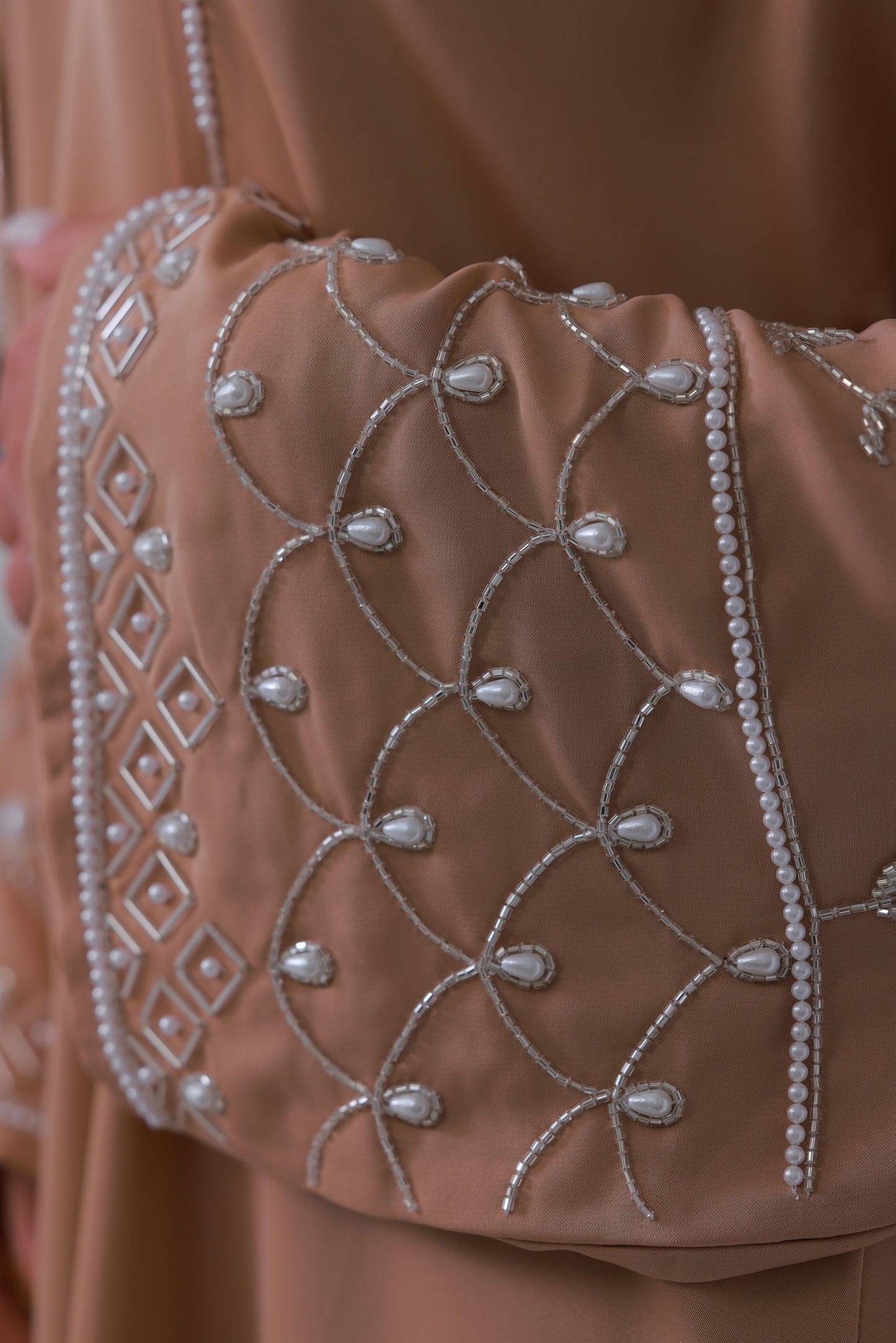 Detail van nude beige abaya stof met luxe borduurpatroon 
