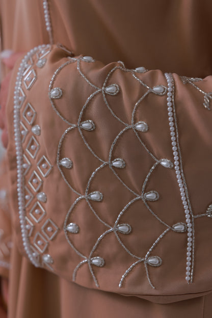 Detail van nude beige abaya stof met luxe borduurpatroon 
