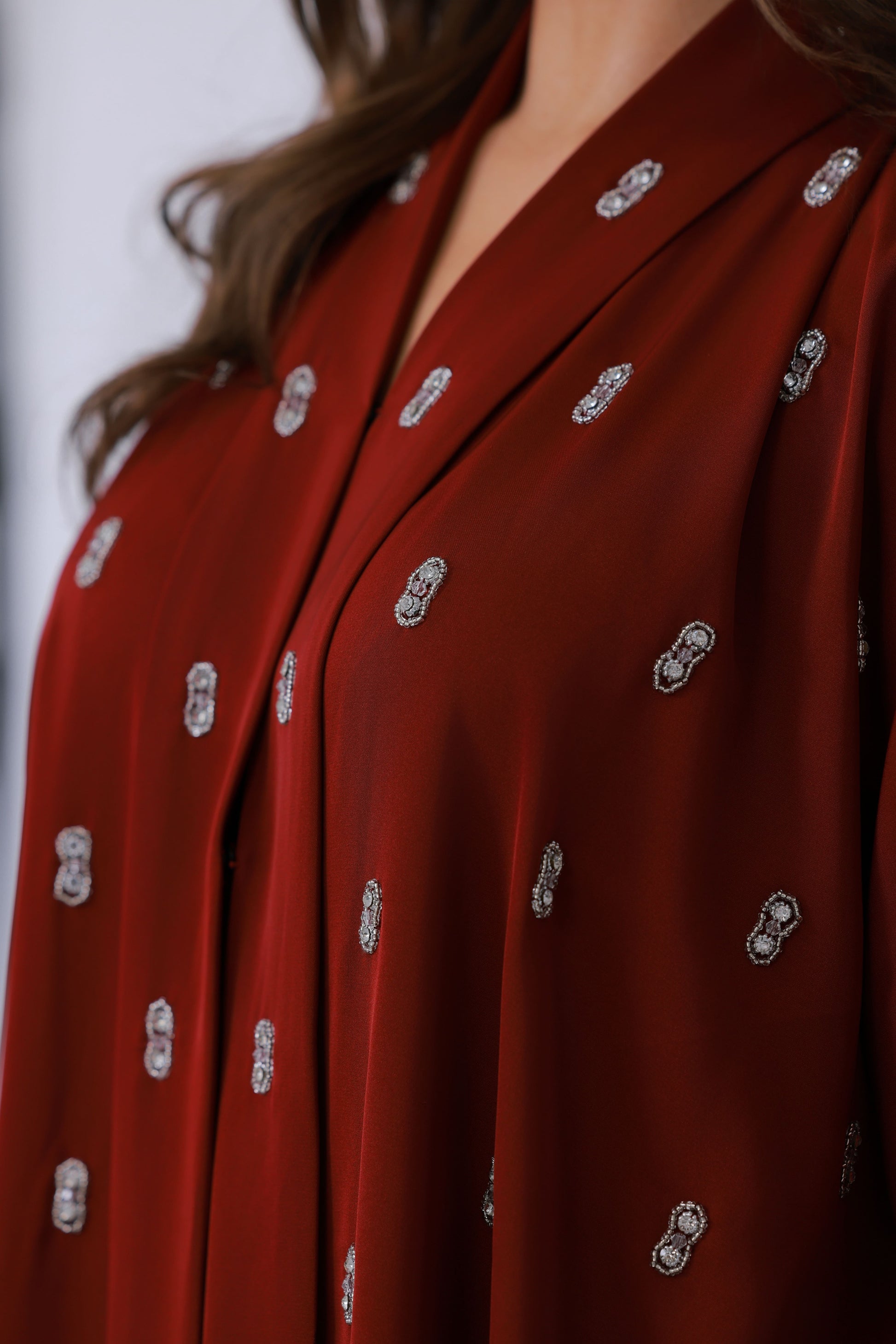 Detail van rode abaya stof met decoratief borduurpatroon
