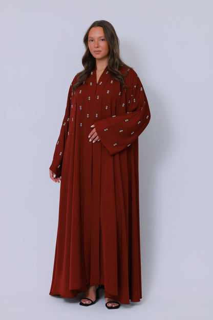 Rode open abaya in schuin perspectief met sierlijk borduurwerk langs de mouwen
